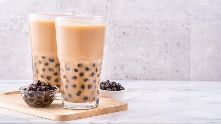 Popular Taiwan drink - Bubble milk tea with tapioca pearl ball in drinking glass on marble white table wooden tray background, close up, copy space