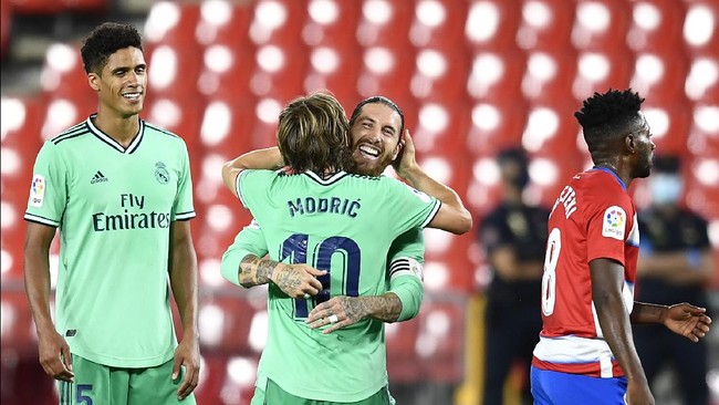 Real Madrid's Sergio Ramos, second right, celebrates his team victory with his teammate Real Madrid's Luka Modric during the Spanish La Liga soccer match between Granada and Real Madrid at the Los Carmenes stadium in Granada, Spain, Monday, July 13, 2020. (AP Photo/Jose Breton)