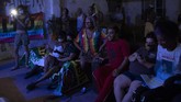 Grup LGBTQ Brazil Bersembunyi dari Virus Corona di Gedung Copacabana Indianara Siqueira, wearing a rainbow colored shirt, sits with fellow residents to watch their weekly presentations performed on a makeshift stage at the squat known as Casa Nem, occupied by members of the LGBTQ community who are in self-quarantine as a protective measure against the new coronavirus, in Rio de Janeiro, Brazil, Saturday, May 23, 2020. Siqueira, 49, a transgender sex worker and activist leads Casa Nem. (AP Photo/Silvia Izquierdo)