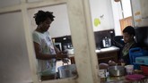Grup LGBTQ Brazil Bersembunyi dari Virus Corona di Gedung Copacabana Morgana keeps Micaela company as she prepares rice balls for lunch in the kitchen of the squat known as Casa Nem, occupied by members of the LGBTQ community who are in self-quarantine as a protective measure against the new coronavirus, in Rio de Janeiro, Brazil, Wednesday, July 8, 2020. Self-imposed lockdown is one of few ways this traditionally marginalized group has found to minimize COVID-19 risks, while others remain vulnerable on the streets. (AP Photo/Silvia Izquierdo)