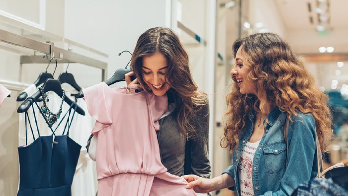 Two young women choosing dresses in a luxury fashion store