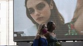 Milan Digital Fashion Week Pedestrians pass by a screen showing a Vivetta model during the Milan Digital Fashion Week, in Milan, Italy, Tuesday, July 14, 2020. Forty fashion houses are presenting previews of menswear looks for next spring and summer and pre-collections for women in digital formats, due to concerns generated by the COVID-19. (AP Photo/Luca Bruno)