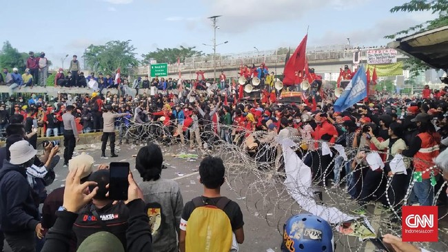 Massa yang melakukan demonstrasi menuntut agar DPR menghentikan pembahasan RUU Ciptaker di depan Gedung DPR/MPR melempari botol minuman ke arah barikade polisi, Kamis (16/7) sore.