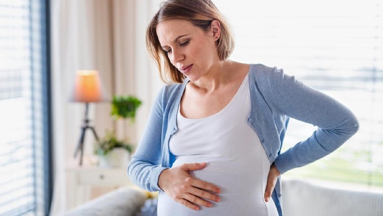 A portrait of pregnant young woman indoors at home, feeling tired.