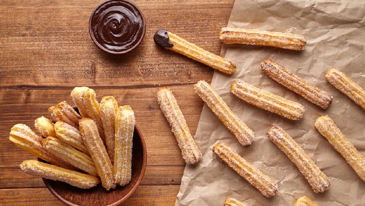 churros - Traditional Spanish and Mexican dessert on a white plate with chocolate sauce on an old grey rustic wooden table&comma; horizontal view from above&comma; close-up&comma; flatlay