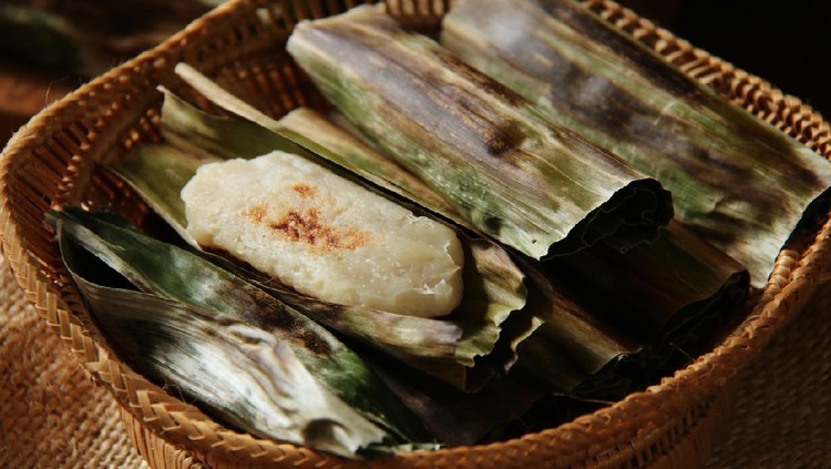 Otak-otak, the traditional snack of grilled fish cake from Jakarta. The fish cake is wrapped in banana leaf then grilled on a charcoal grill. The fish cakes are arranged on a bamboo basket with one of the cakes shown unwrapped.