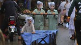 Nyalang Edisi 18 Juli 2020 Youths cover their faces with plastic bags while pushing a handcart during rainfall in Peshawar, Pakistan, Sunday, July 12, 2020. (AP Photo/Muhammad Sajjad)
