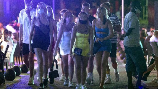 Tourists walk at the resort of Magaluf on the Spanish Balearic island of Mallorca, Spain, Thursday morning, July 16, 2020. Authorities in Spain's Balearic Islands are pulling the plug on endless drunken nights to the beat of techno music by closing bars and nightclubs in beachfront areas popular with young and foreign visitors. (AP Photo/Joan Mateu)