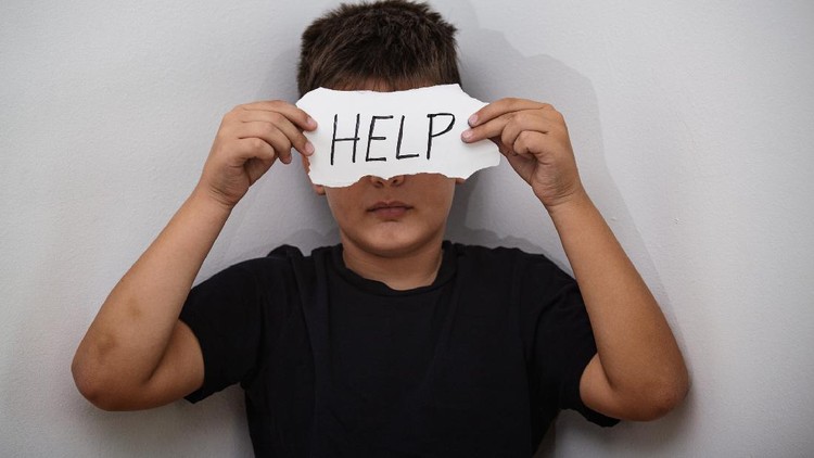 HELP, Teenager with help sign. Boy holding a paper with the inscription. Kid holding sheet of paper with word HELP on grey wall background.