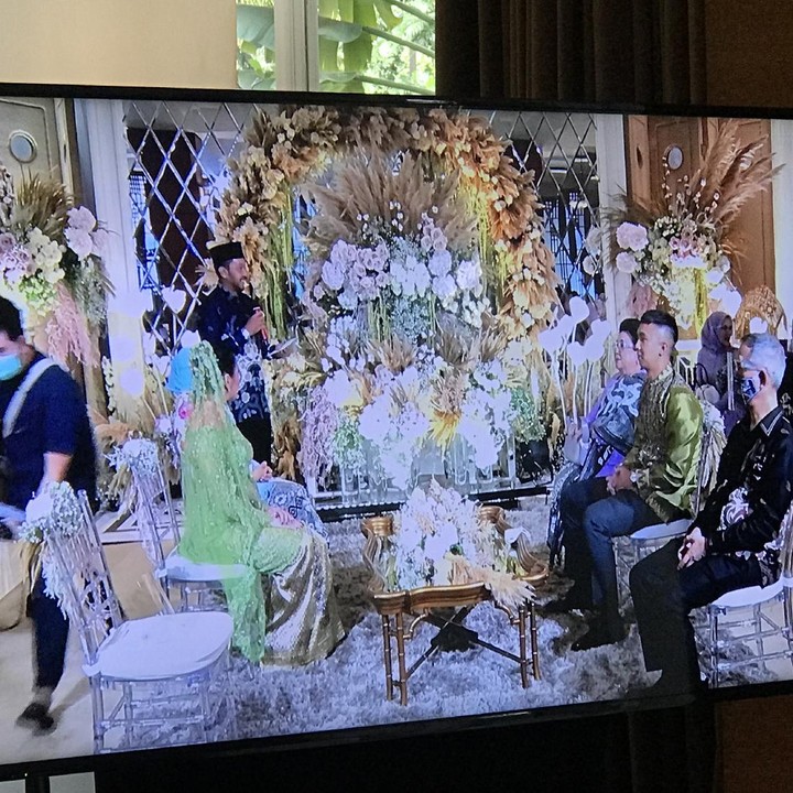 <p>Nikita yang mengenakan kebaya dan veil hijau duduk berhadapan dengan Indra, yang mengenakan batik senada.</p>