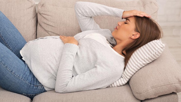 1178537750 Pregnant woman feeling bad suffering from pain lying on couch at home. Sickness during pregnancy