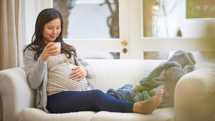 Shot of an attractive young pregnant woman drinking an iced coffee while relaxing on the sofa at home