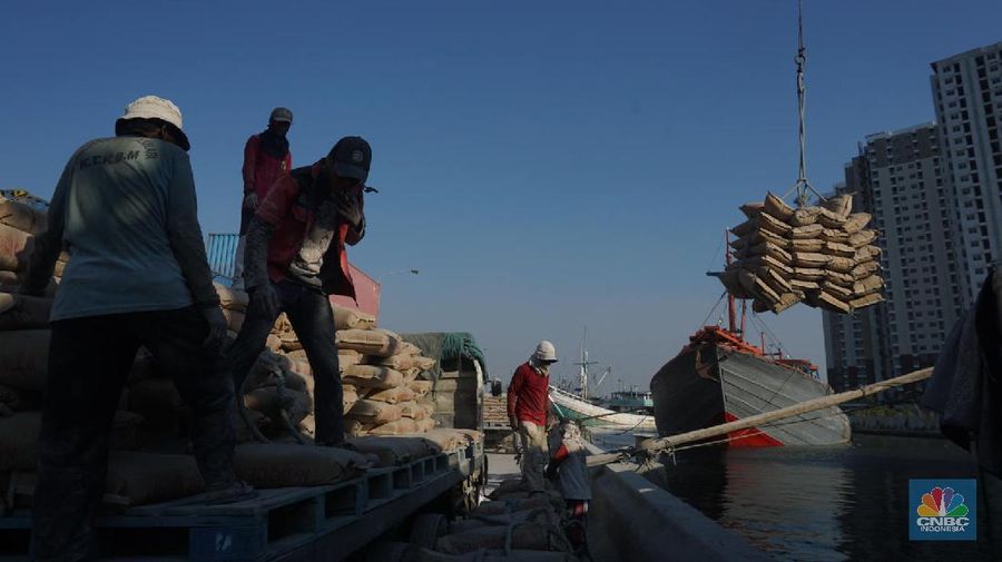Sayup suara ombak menyusup hingga ke ruang-ruang sempit Kapal yang tengah bersandar di Pelabuhan Sunda Kelapa, Jakarta Utara, Rabu (29/7/2020) petang itu. Sejumlah anak dengan berani tengah asik melompat bergantian dari atas kapal, sambil berteriak. Sunda Kelapa adalah nama pelabuhan yang berada di ujung utara Jakarta. Pelabuhan ini sudah ada sejak ratusan tahun lalu. Pada zaman kerajaan, Sunda Kelapa adalah pusat perdagangan. Kini, meski telah dimakan usia, pelabuhan ini masih tetap ramai. Banyak orang mengais rezeki di Pelabuhan Sunda Kelapa. Ada pedagang, nelayan, Anak Buah Kapal (ABK), pemberi jasa sampan, hingga buruh angkut. Semua tumpah ruah menjadi satu. Namun bagi anak-anak sunda kelapa adalah tempat paling asik untuk bermain. Pelabuhan Sunda Kelapa lambat laun tidak terlihat sesibuk saat masa jayanya. Kini, pelabuhan tersebut dikelola oleh PT Pelindo II dan tidak mengantongi sertifikasi International Ship and Port Security karena sifat pelayanan jasanya hanya untuk melayani kapal antar pulau di dalam negeri. Dari sisi ekonomi pelabuhan ini masih cukup strategis, mengingat berdekatan dengan pusat-pusat perdagangan di Jakarta seperti Glodok, Pasar Pagi, Mangga Dua, dan lain-lainnya. Menjadi buruh kuli angkut mungkin bukan hal yang dicita-citakn oleh banyak orang. Namun ketika tidak ada lagi keahlian yang bisa ditawarkan selain tenaga kasar maka menjadi buruh kasar sebagai kuli angkut pun harus dijalani. Setidaknya ini yang tertangkap saat melihat potret para kuli angkut di Pelabuhan Sunda Kelapa Jakarta Utara. Dalam sehari para pekerja kuli angkut ini mampu membongkar muatan dengan berat total 300ton. Beban sebesar ini dikerjakan oleh 20an orang pekerja. (CNBC Indonesia/ Muhammad Sabki)