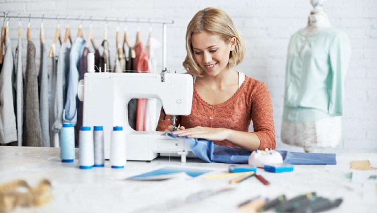 A beautiful young seamstress sitting and sewing at a sewing machine