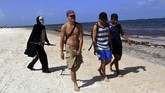 FOTO: Santai di Pantai bersama 'Malaikat Pencabut Nyawa' Pria berpakaian Santa Muerte berjalan-jalan di sebuah pantai di Meksiko demi mengingatkan pengunjung bahwa jumlah kematian COVID-19 bukan sekadar angka.