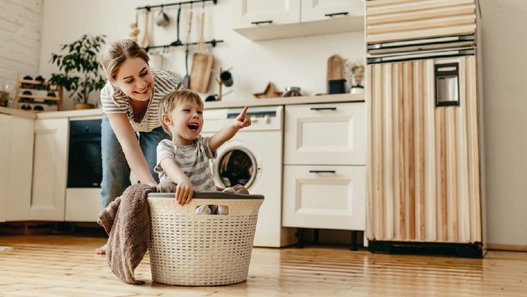 Happy family mother housewife and child son in laundry with washing machine