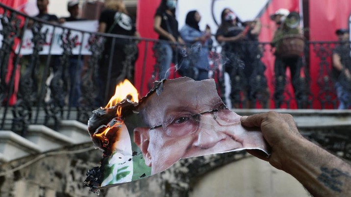 Seorang pengunjuk rasa anti-pemerintah membakar foto Presiden Lebanon Michel Aoun di dalam kementerian luar negeri Lebanon di Beirut, Lebanon, Sabtu, 8 Agustus 2020. (AP/Bilal Hussein)