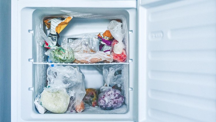 Shot of an open freezer packed with frozen food in plastic bags