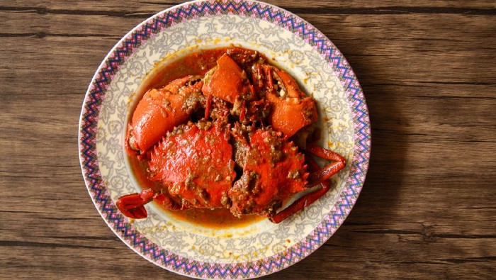 Crab in Padang sauce or Padang crab (Indonesian: Kepiting saus Padang) on wood background.