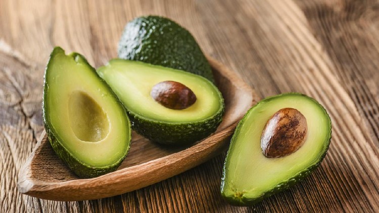 Ilustrasi buah alpukat Avocado on old wooden table in bowl. Halfs of avocados fresh fruits healthy food.