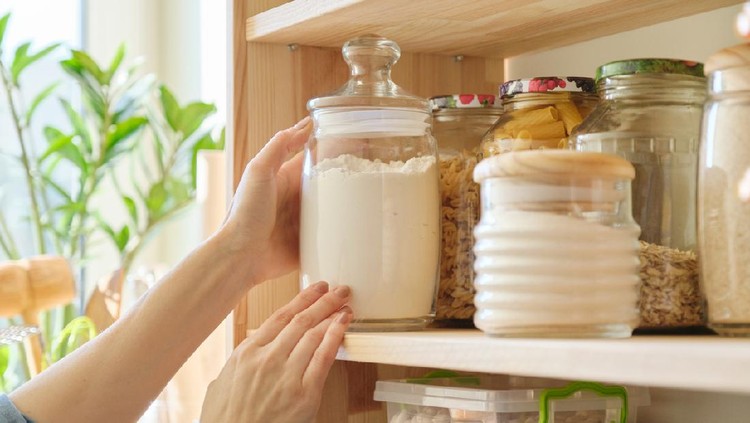 Food products in the kitchen storing ingredients in pantry. Woman taking jar of flour