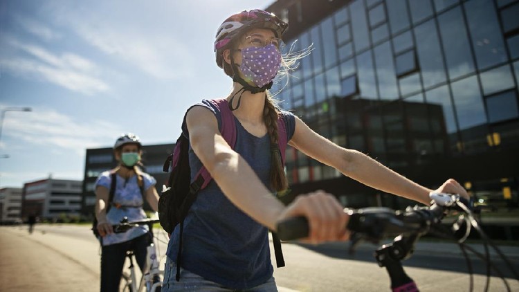 Bersepeda Mother and daughter are enjoying a bike trip together in the modern residential area. They are wearing obligatory face masks.

Nikon D850