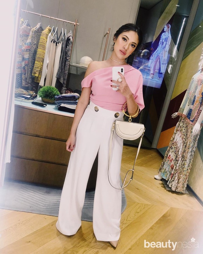 Cynthia kali ini mengenakan atasan sabrina merah muda dengan palazzo putih lengkap dengan handbag di lengannya. Tampilannya selalu terlihat simpel namun elegan. Gaya makeupnya juga menyesuaikan dengan warna outfit yang dipakainya. (Foto: Instagram.com/Cynthiaganesha)