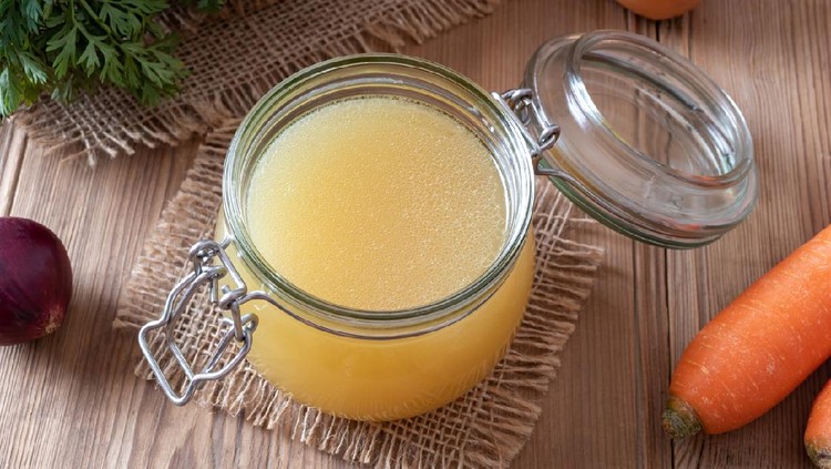 Chicken bone broth in a glass jar and fresh vegetables