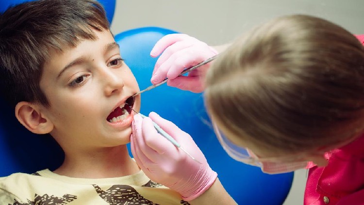 1268390922 Teenager boy patient at the dentist. A boy with problem teeth sitting in a dental chair