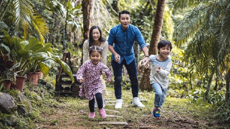 Laughing mid adult Chinese parents encouraging their energetic son and daughter as they race each other toward the camera.