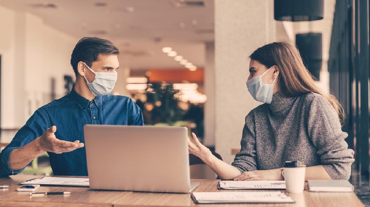 close up. business colleagues in protective masks sitting at the office Desk.