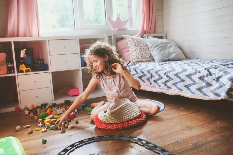 child girl cleaning her room and organize wooden toys into knitted storage bag. Housework and help concept