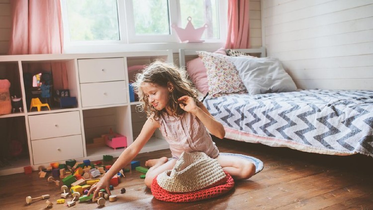 child girl cleaning her room and organize wooden toys into knitted storage bag. Housework and help concept