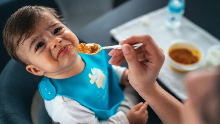 Mother feeding the cry baby son with a spoon