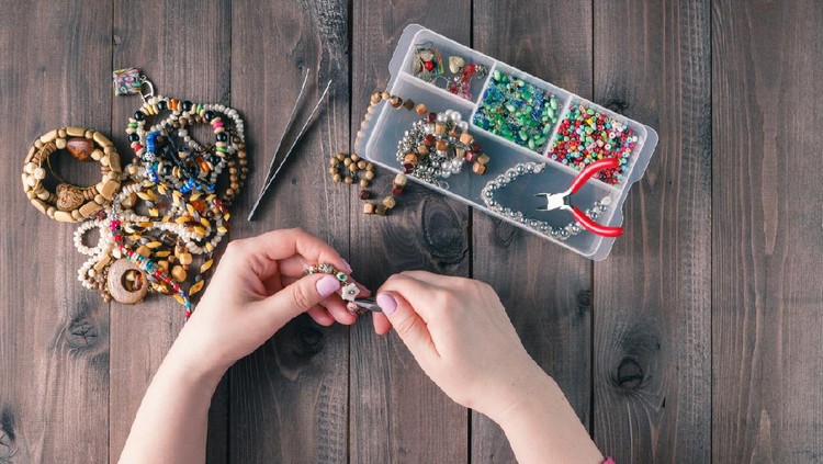 Making of handmade jewellery. Box with beads on old wooden background. Handmade accessories. Top view