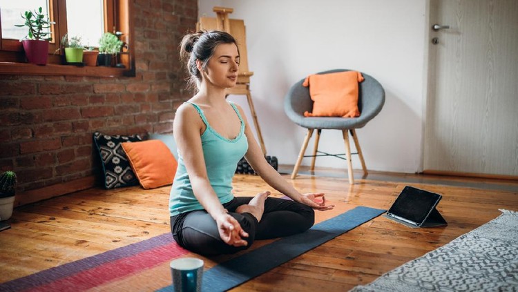 Olahraga yoga Young woman relaxing herself practicing meditation at her home