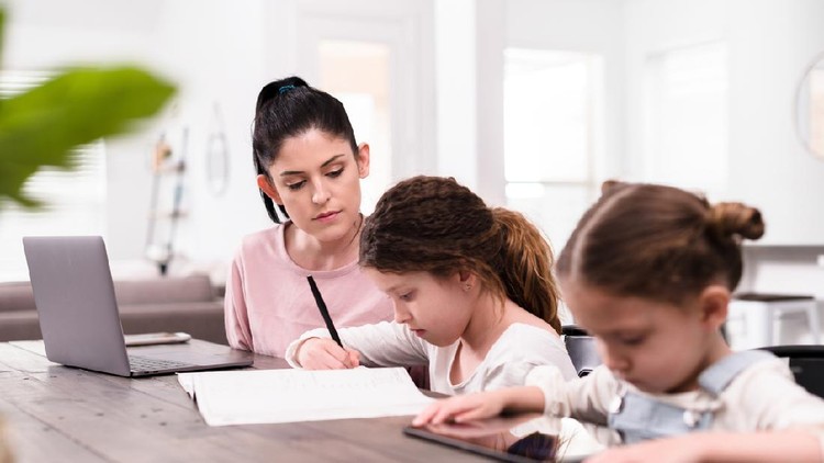 sekolah di rumah A confident mid adult mom teaches her two young daughters at home while under stay-at-home order during coronavirus crisis.