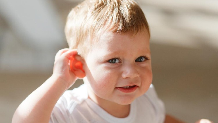 kuping anak baby boy listens to put a hand to his ear.