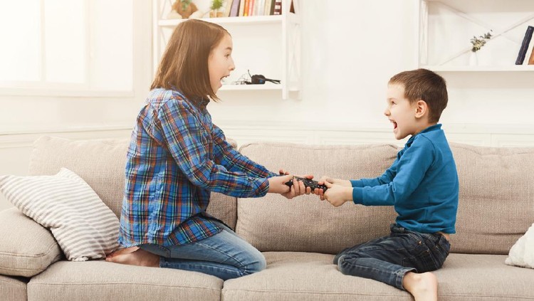 Sibiling conflict atau sibling rivarly Siblings fighting over remote control at home, brother and sister have quarrel, copy space