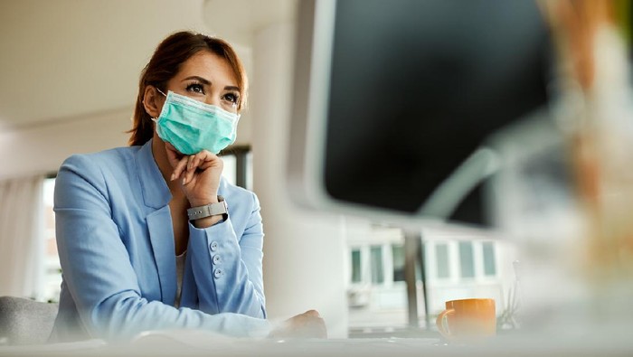 Low angle view of businesswoman with face mask working on desktop PC in the office.