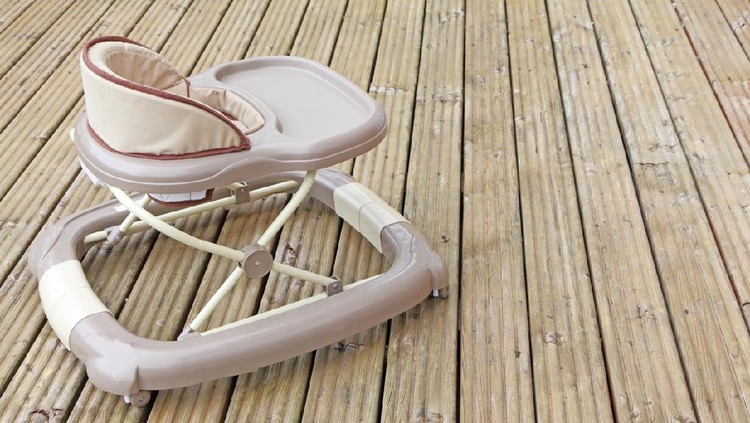 A brown generic baby walker outside on the decking