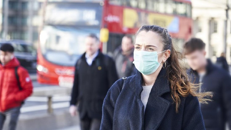Young woman wearing face mask while walking in the streets of London
