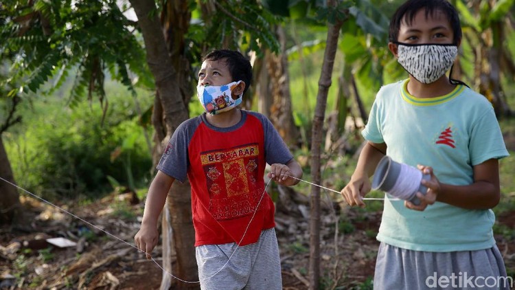 Sejumlah anak bermain layang-layang di kawasan Jakarta Barat. Anak-anak itu tampak mengenakan masker saat bermain layang-layang di lapangan terbuka.