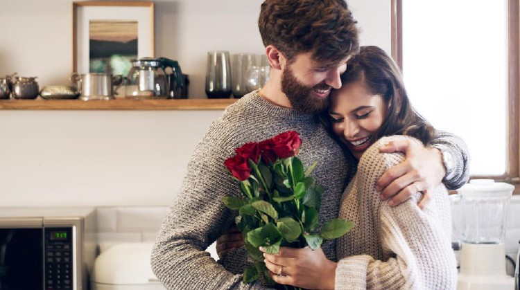 Shot of a young man surprising his wife with a bunch of roses at home