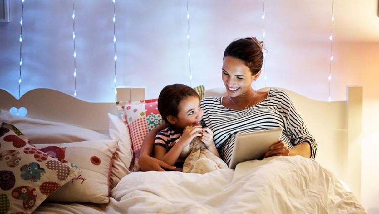 Shot of an attractive young pregnant woman reading her daughter a bedtime story on a tablet