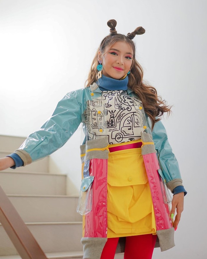 Inspirai fashion 90-an ala Tiara satu ini memberikan kesan riang dan menyenangkan. Jaket transparan dengan detail lengan warna biru dan bagian bawah pink cerah. Kombinasikan dengan inner monokrom dan mini skirt warna kuning. Pilih celana berwarna merah supaya penampilan terlihat makin cheerful. (Foto: www.instagram.com/tiaraandini/)