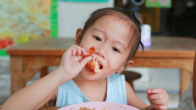Close up of little asian girl eating shrimp.