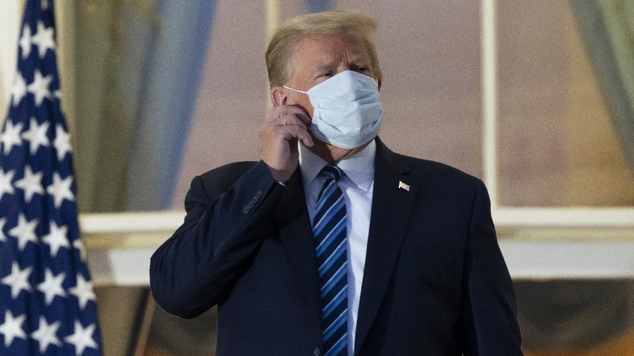 President Donald Trump removes his mask as he stands on the Blue Room Balcony upon returning to the White House Monday, Oct. 5, 2020, in Washington, after leaving Walter Reed National Military Medical Center, in Bethesda, Md. Trump announced he tested positive for COVID-19 on Oct. 2. (AP Photo/Alex Brandon)