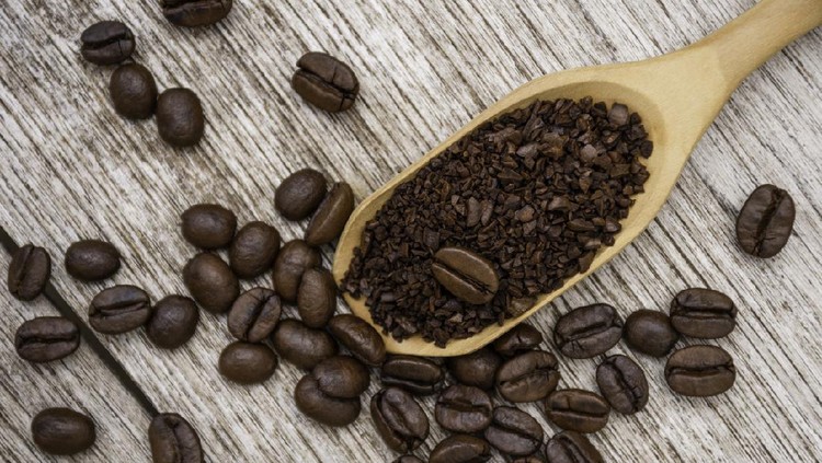 Closeup instant granulated coffee in wooden scoop with roasted coffee bean isolated on old rustic wood table  background. Top view. Flat lay.