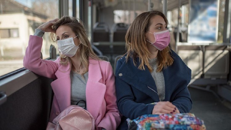 Ilustrasi Corona di tempat umum Two young women at public transport during virus epidemic. Two women sitting at public transport wearing pollution masks.